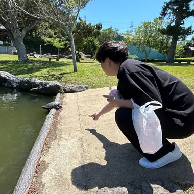 公園の池のほとりでしゃがんでいるところ