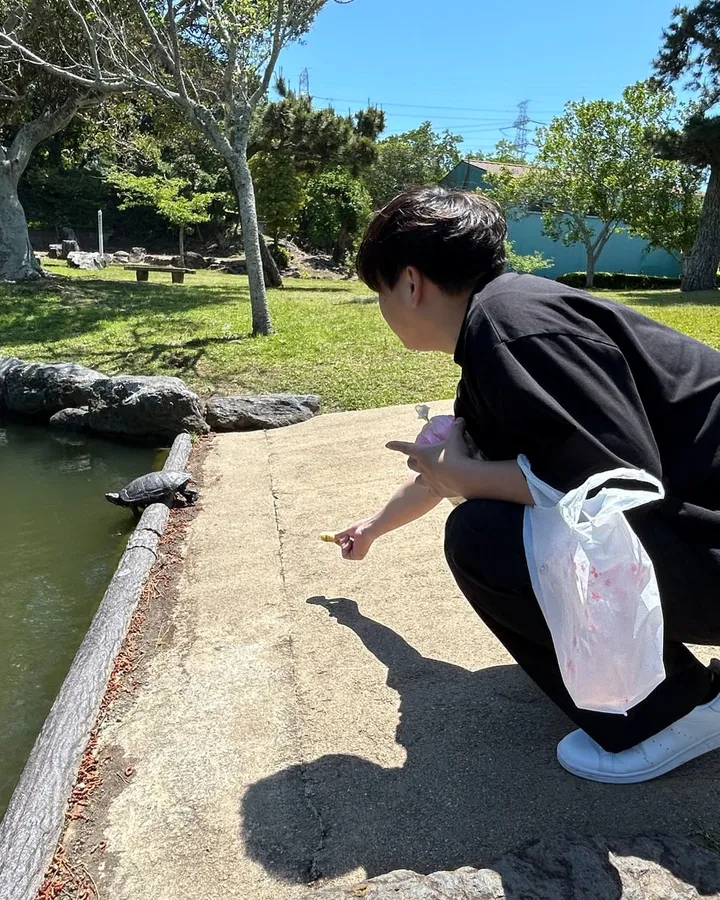 公園の池のほとりでしゃがんでいるところ