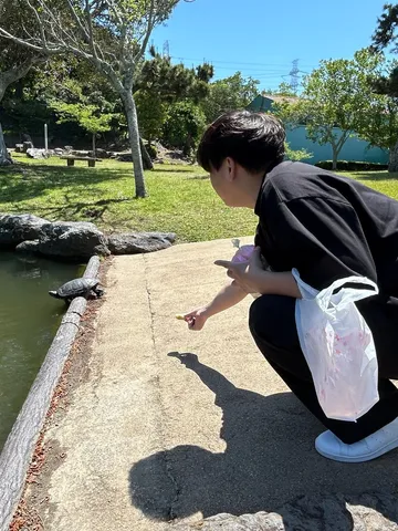 公園の池のほとりでしゃがんでいるところ